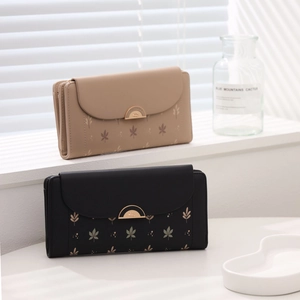 Detail of elegant bifold wallets with leaf print and gold hardware in beige and black