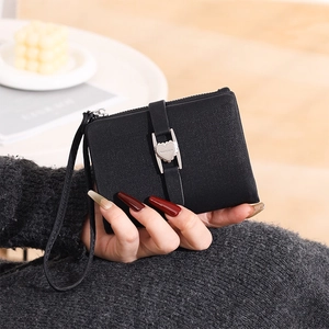 Detail of black textured leather wallet featuring a silver heart buckle and wrist strap