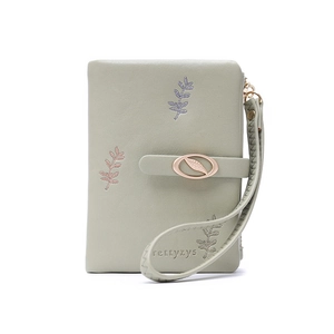 Detail of light green PU leather wallet featuring leaf embroidery and leaf metal clasp