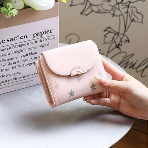 Détail d'un petit portefeuille rose pour femme avec motif feuille et boucle dorée
