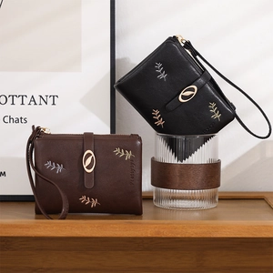 Detail of short PU leather wallets with leaf embroidery and gold leaf pendant decoration