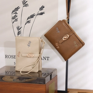 Detail of short PU leather wallets in beige and brown with floral embroidery and wrist strap