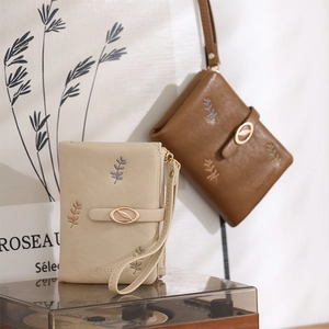Detailed view of beige and brown embroidered PU leather short wallets for women.