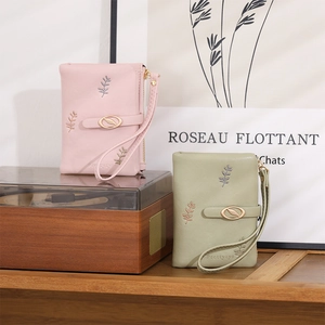 Detail of short PU wallets with leaf clasp and embroidery in pink and green