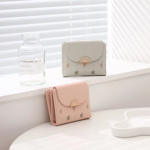 Détail de petits portefeuilles à fleurs avec imprimé feuilles et fermoir en rose et gris