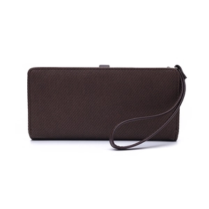 Macro detail of dark brown twill fabric long wallet with leather wrist strap and strap