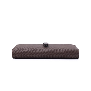 Side view of dark brown striped long wallet featuring a secure metal clasp and textured finish