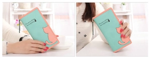 Detail of mint green PU leather wallet with cat patch and embroidery in model's hand