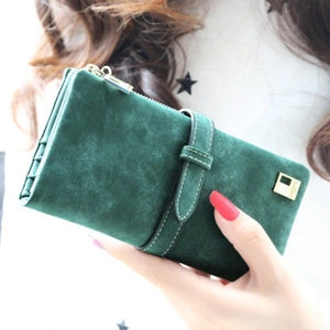 Detail view of dark green matte suede long wallet with gold zipper and metal logo plate
