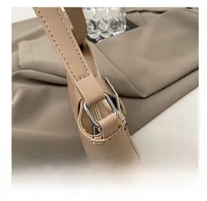 Gros plan du sac bicolore montrant les coutures blanches et les ferrures métalliques argentées