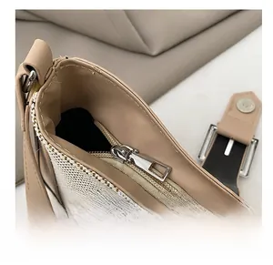 Détail de la fermeture éclair argentée et du tissu texturé crème sur un sac à bandoulière
