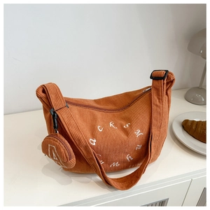 Detail of orange corduroy crescent bag with white embroidery and mini round coin pouch