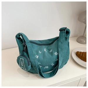 Close-up of dark green corduroy crossbody bag texture and small coin purse attachment