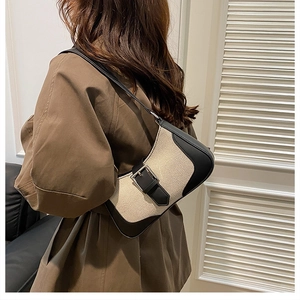 Détail du sac croissant en toile beige et cuir noir avec boucle argentée sur l'épaule