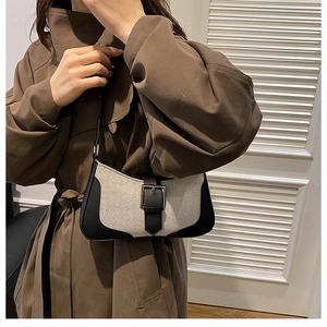Vue détaillée du sac bandoulière en toile beige et cuir noir avec boucle métallique argentée
