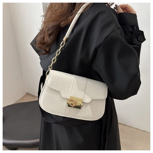 Detail of white crocodile pattern shoulder bag featuring golden clasp and chain strap
