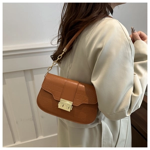 Brown crocodile pattern shoulder bag with gold clasp and chain strap on a model