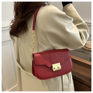 Detail of burgundy crocodile pattern crossbody bag with gold lock and chain strap