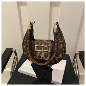 Detail of leopard print crescent bag with golden metal buckle on minimalist background