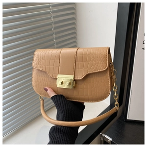 Close-up of light brown crocodile texture leather and golden metal buckle on a handbag