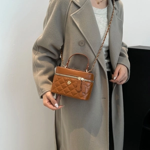 Brown quilted leather crossbody bucket bag with floral badge and chain strap