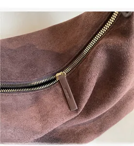Detailed macro view of the smooth gold metal zipper on a dark brown suede tote bag