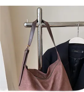 Detail of a brown suede hobo tote bag featuring a zipper closure and adjustable strap