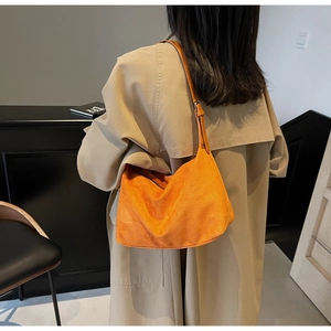 Detail of soft matte orange suede tote bag with stylish shoulder strap and rich texture