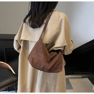 Minimalist large brown matte leather tote bag worn as a shoulder bag on a female model