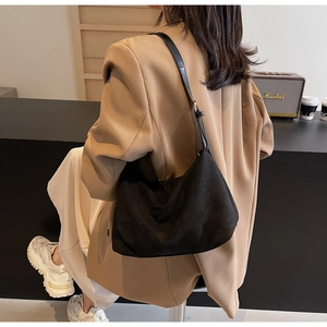 Detail of a large matte black hobo bag styled with a brown blazer and white trousers