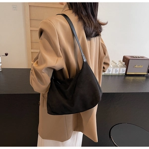 Minimalist black suede hobo bag with sleek shoulder strap shown in a modern lifestyle setting
