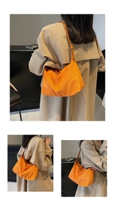 Detail of bright orange suede hobo bag with a minimalist silhouette and leather strap