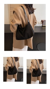 Detail of minimalist black matte suede crescent bag showing shoulder strap and sleek texture