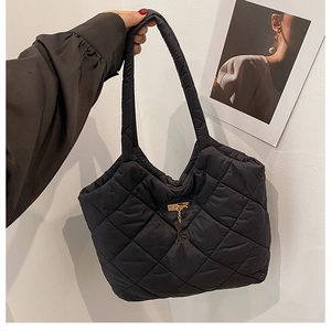 Macro detail of black quilted puffer tote bag featuring golden deer charm and stitching