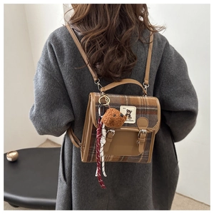 Detail of a mini plaid backpack with brown teddy bear charm on a grey wool coat