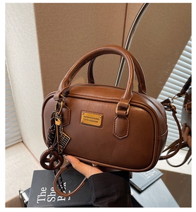 Nahaufnahme der braunen Vintage-Bowlingtasche mit Goldplakette und Abakus-Anhänger