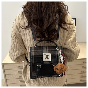 Detail of plaid mini backpack with bear patch and plush puppy charm in retro style