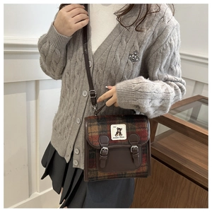 Detail of vintage plaid shoulder bag with bear patch and premium leather stitching