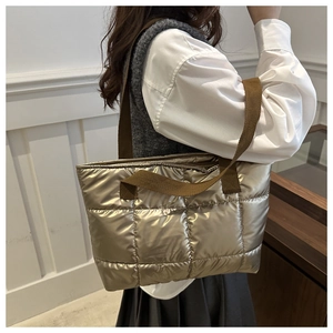 Detailed shot of metallic champagne quilted tote bag with wide brown shoulder straps