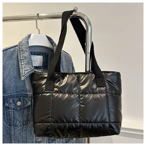 Détail d'un sac cabas noir matelassé suspendu sur un support métallique minimaliste
