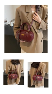 Detailansicht der weinroten Henkeltasche mit Lederstruktur und goldener Hardware