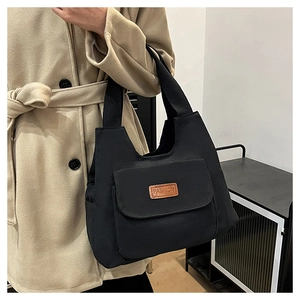 Dettaglio della borsa tote in tela nera con etichetta in pelle fashion e trama della tasca