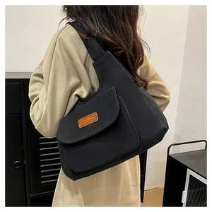 Vue détaillée du grand sac cabas en toile noire avec poche avant et étiquette mode