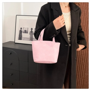 Detail of pink pleated soft leather handbag with dual top handles worn by a model