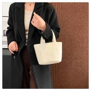 Minimalist cream soft leather handbag with dual handles shown in a lifestyle setting