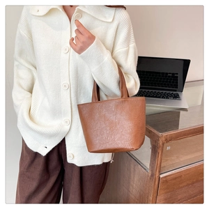 Close-up of brown vintage leather handbag styled with an autumn knit cardigan outfit