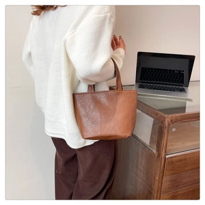 Detailed texture of a vintage brown soft leather mini tote bag held by a person