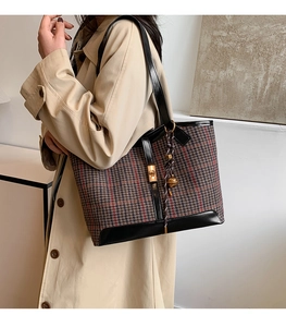 Detail of wool tote bag featuring brown houndstooth pattern and gold twist lock closure