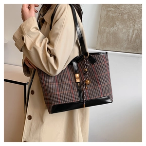 Detail of vintage plaid tweed tote bag with black leather trim and golden metal lock