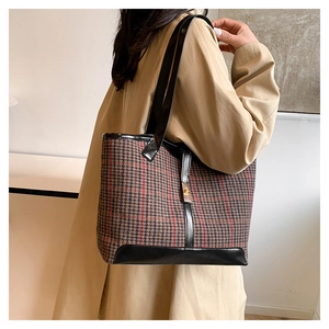 Close-up of houndstooth tote bag featuring red accents and black leather details